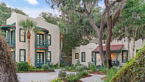 A building with a stucco exterior, green shutters, and a red-tiled roof. - Village Inn and Pub - Adults Only (St. Simons Island)