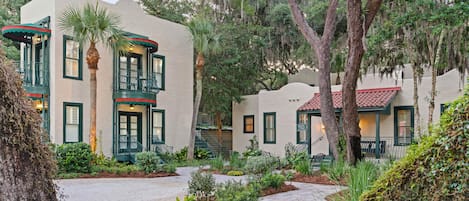A building with a stucco exterior, green shutters, and a red-tiled roof.