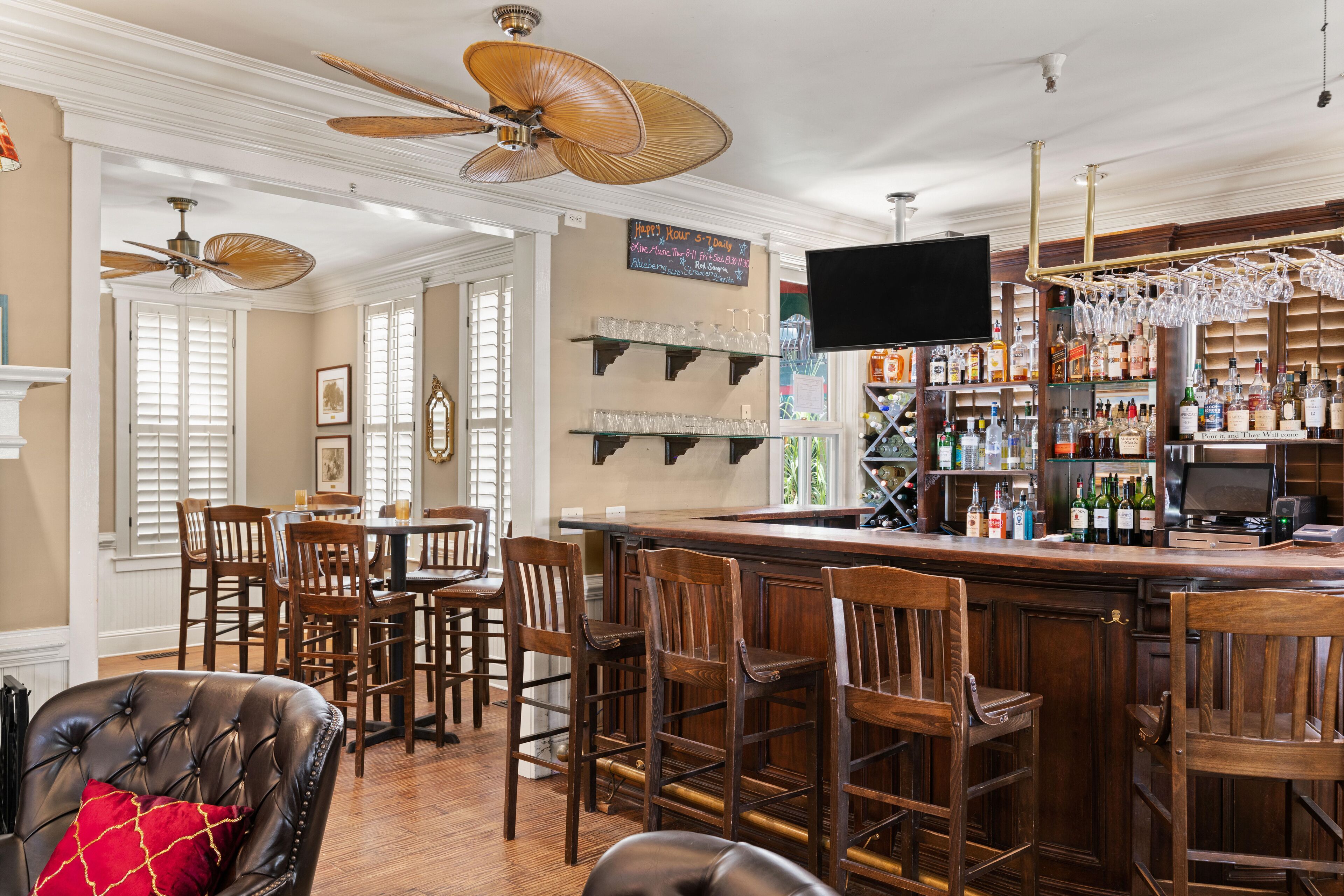 A bar area with wooden chairs, a bar counter, and a television screen.