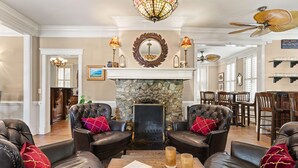 A spacious living room with leather armchairs, a fireplace, and a dining area. - Village Inn and Pub - Adults Only (St. Simons Island)