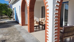 A covered outdoor seating area with a bench and a table, brick arches, and a door leading to a room. - Entire villa, large spaces, 5 minutes walk to the beach suitable for families groups (Villaggio San Leonardo)