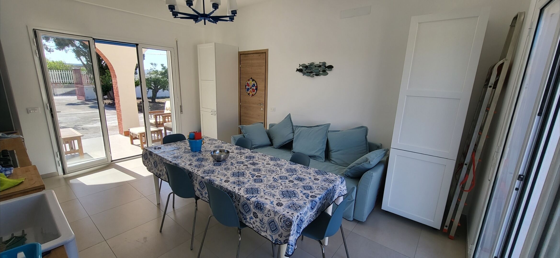 A dining area with a table covered in a patterned tablecloth, blue chairs, and a blue sofa.