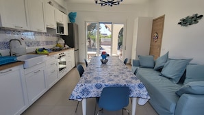 A compact kitchen with white cabinets, a tiled backsplash, and a dining area with a patterned tablecloth. - Entire villa, large spaces, 5 minutes walk to the beach suitable for families groups (Villaggio San Leonardo)