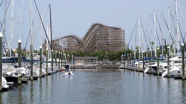 A marina with boats docked and a large building with scaffolding in the background.