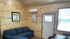 A cozy room with a blue sectional sofa, a dining table with chairs, a framed picture on the wall, and a window with blinds.