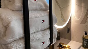 A bathroom with a modern design, featuring a large mirror with a circular light, a gold faucet, and neatly folded white towels with a small logo. - 5min Palais, Luxury&Cinema Studio,Croisette,Forville,beaches (Cannes)