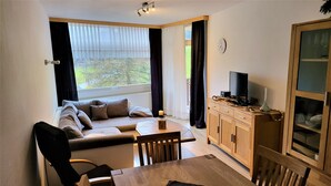 A cozy living room with a sofa, a dining table, and a TV. - Fewo Luchsauge im Ferienresort mit Pool (Schluchsee)