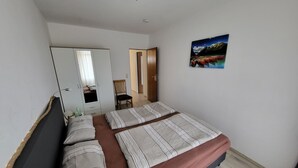 A bedroom with a bed, a wardrobe, a chair, and a painting on the wall. - Fewo Luchsauge im Ferienresort mit Pool (Schluchsee)