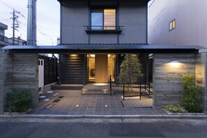 A modern building with a flat roof, a visible entrance, and a small tree in the foreground.