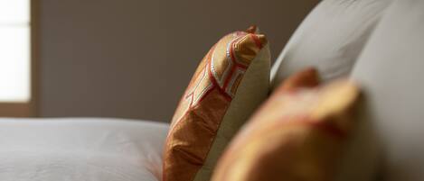 A close-up of a bed with a patterned pillow and a plain pillow.