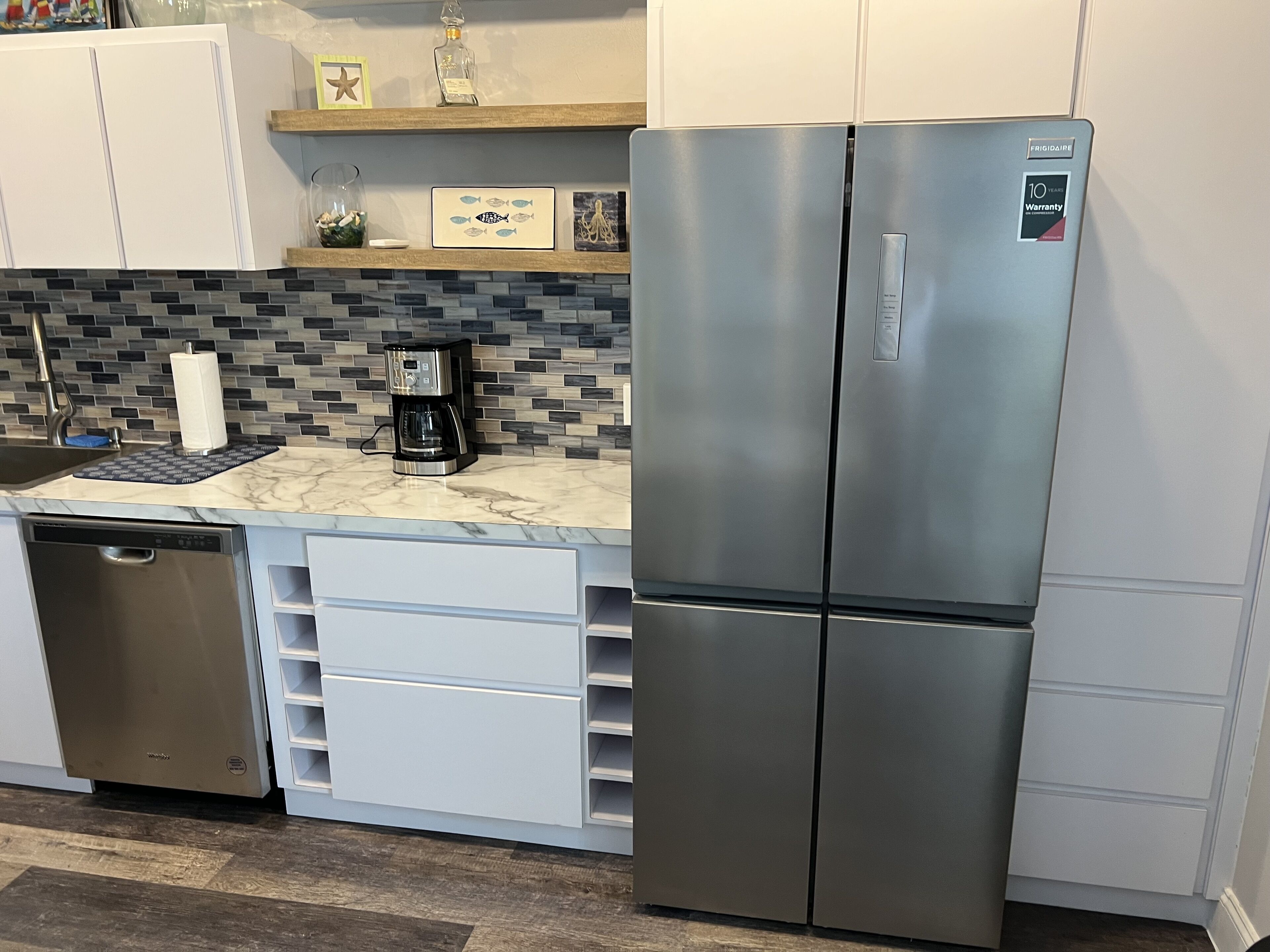 A kitchen with a stainless steel refrigerator, a coffee maker, and a dishwasher.
