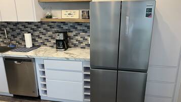 A kitchen with a stainless steel refrigerator, a coffee maker, and a dishwasher.
