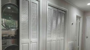 A hallway with white paneled walls and doors, a laundry area with a washing machine, and a radiator on the floor. - 3 min walk to beach! (Jekyll Island)