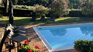 Un área de piscina con sillones de descanso y vistas a un paisaje montañoso.