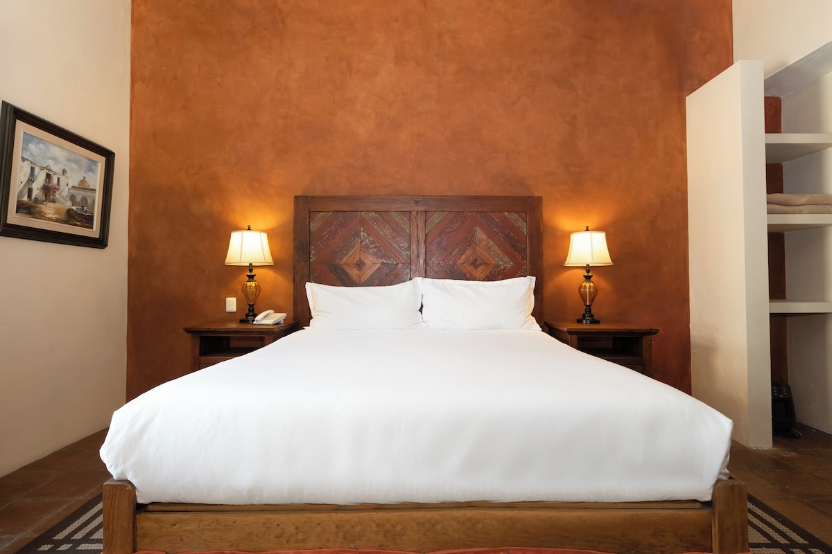 A bed with white linens, two bedside lamps, and a wooden headboard.