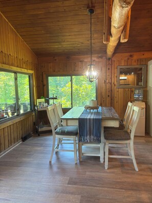 Un intérieur en bois comprenant une table à manger, des chaises et un luminaire suspendu.