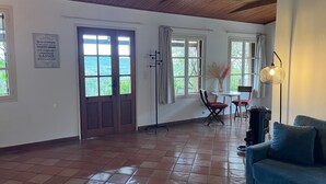 A spacious room with a tiled floor, a wooden ceiling, and large windows offering a view of the outdoors. - Maison Individuelle au Cœur du Maquis Corse (Porto-Vecchio)