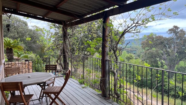 A wooden deck with a table and chairs, overlooking a lush landscape with trees and a view of the countryside. - Maison Individuelle au Cœur du Maquis Corse (Porto-Vecchio)