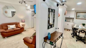 Un salon moderne avec un canapé marron, une table basse et un coin repas comprenant une petite table et des chaises.