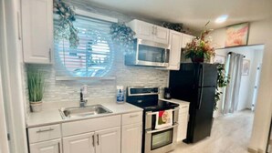 A modern kitchen with white cabinets, a stainless steel sink, a black refrigerator, and a microwave. - Feel at home ! Only 5 min from the Beach ! (Clearwater)