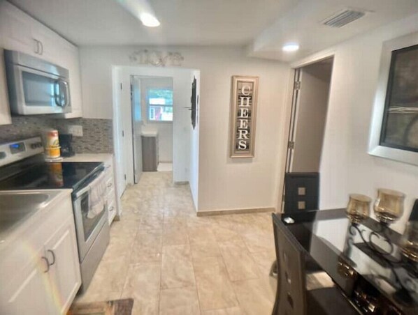 Una cocina moderna con electrodomésticos de acero inoxidable, piso de baldosas y un letrero que dice 'CHEERS'.