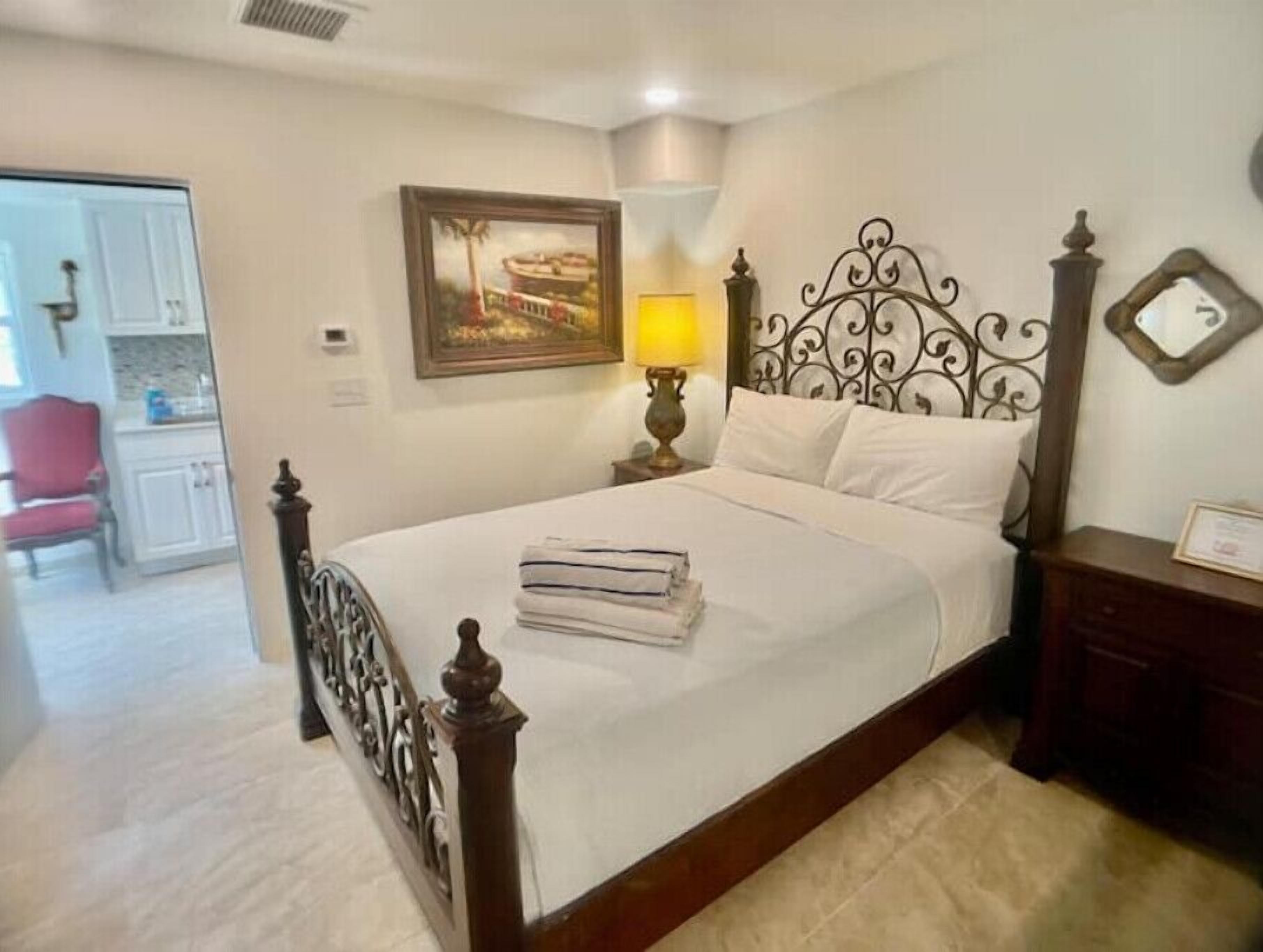 A neatly made bed with a headboard, a bedside lamp, and a framed picture on the wall.