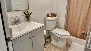 A bathroom with a white sink, a toilet, and a shower curtain. - Loving Apartment! (Clearwater)