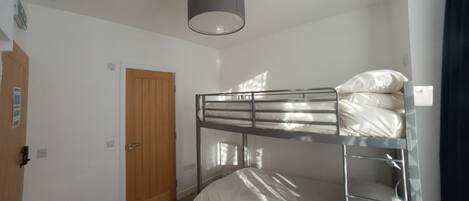 A bunk bed room with a wooden door and a ceiling light fixture.