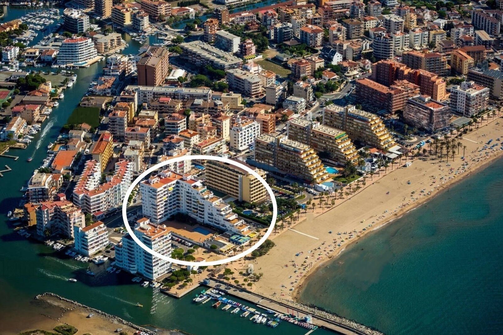 Oversigtsbillede af en kystby med lystbådehavn, tæt bebyggelse og en strand.