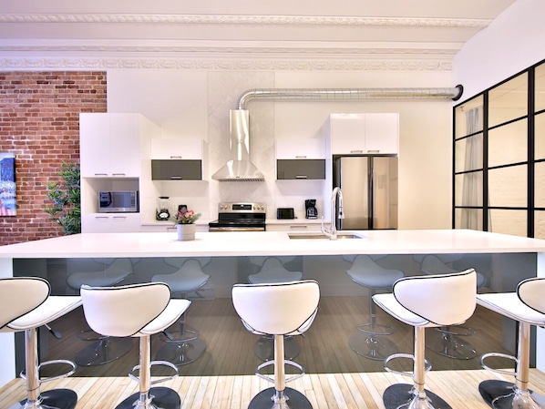 A modern kitchen with white cabinets, stainless steel appliances, and a large island with bar stools.