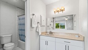 Een badkamer met toilet, douche, wastafelmeubel en een spiegel met verlichting.