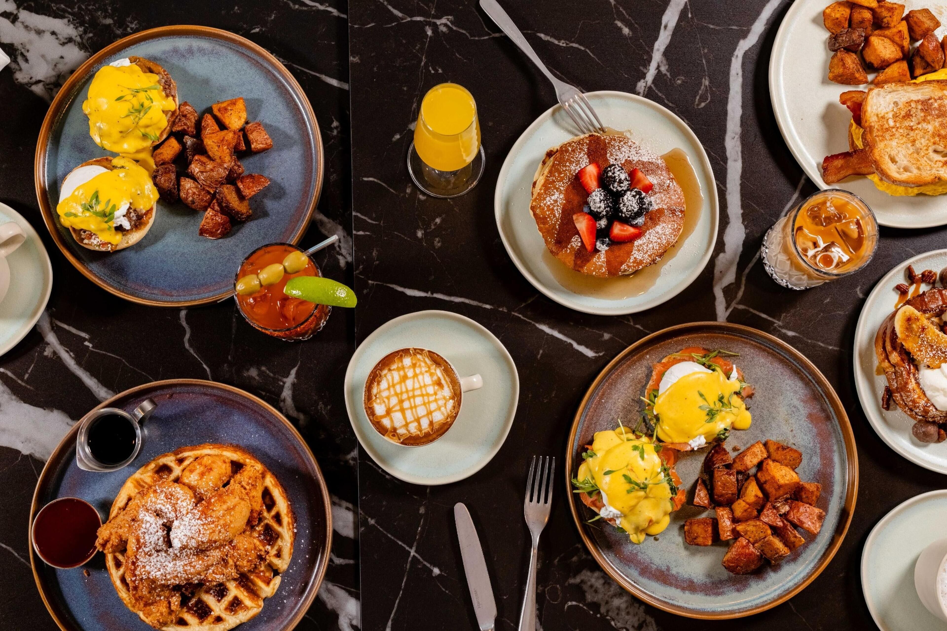 A breakfast spread with various dishes including eggs, waffles, and potatoes.