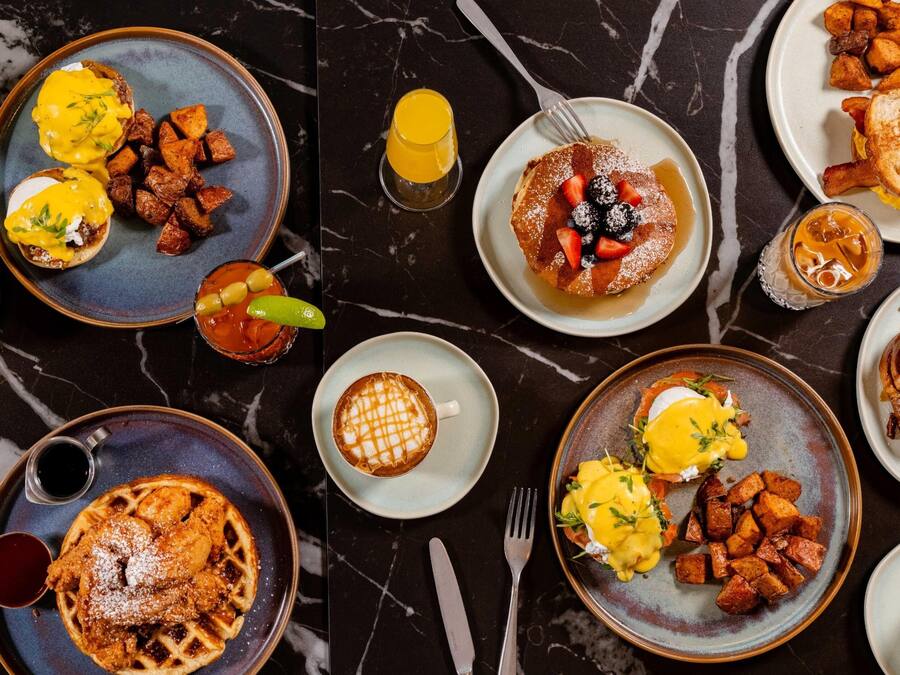 A breakfast spread with various dishes including eggs, waffles, and potatoes.