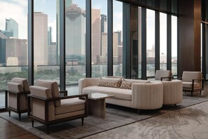 A modern living room with a large window, a sofa, armchairs, and a coffee table. - Thompson Houston, by Hyatt (Houston)