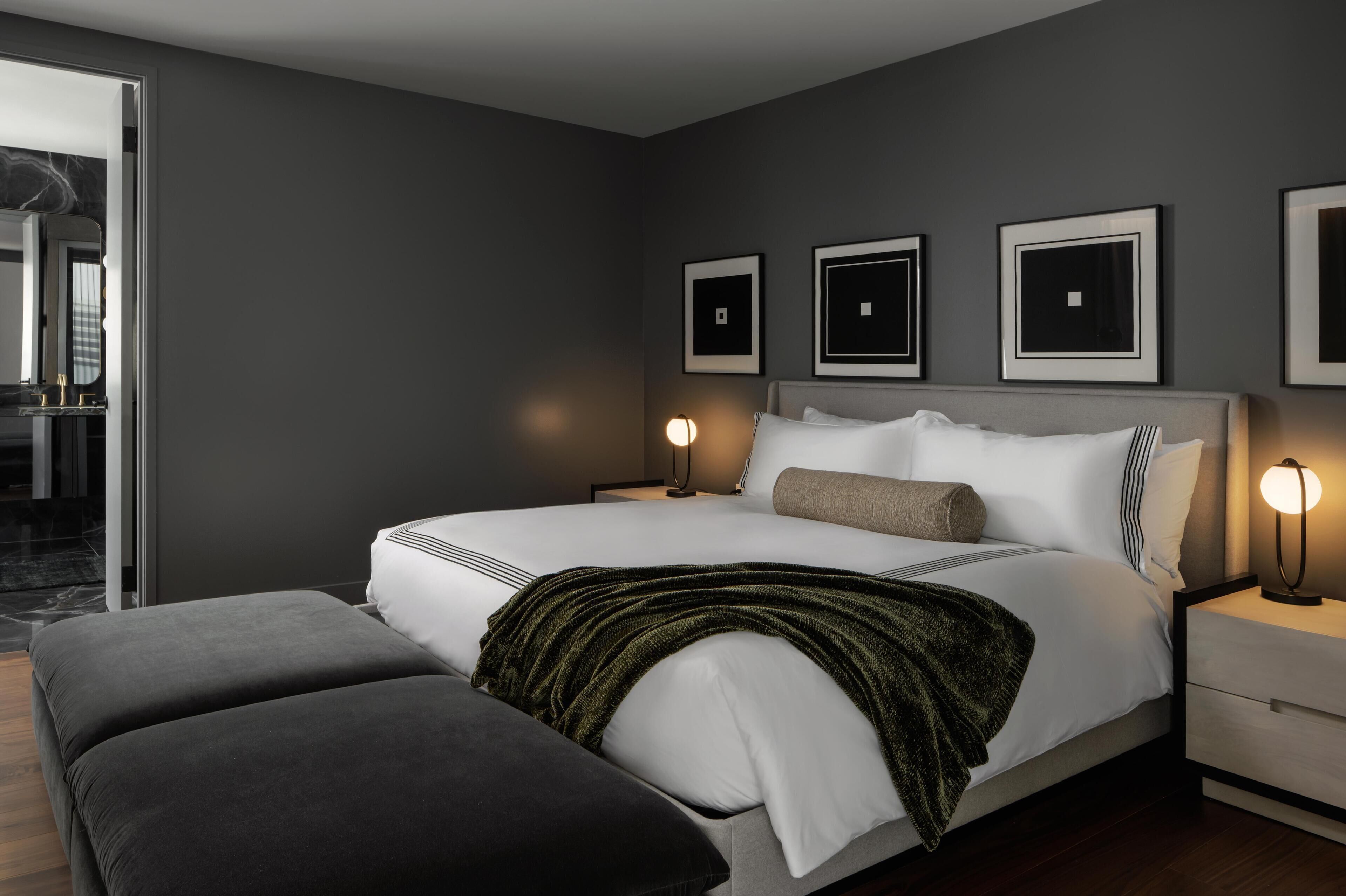 Ein modernes Schlafzimmer mit einem großen Bett, Nachttischen und Blick ins Badezimmer.