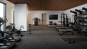 A modern gym with various exercise equipment, a large mirror, and a television on the wall.