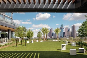 A modern building with a glass facade, a green lawn, and white planters.