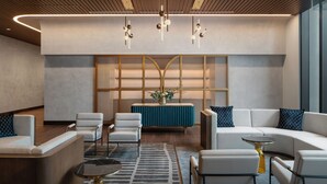 A modern lobby with a reception desk, seating area, and a decorative plant centerpiece.