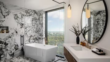 Un baño moderno con una bañera grande, ducha con cerramiento de vidrio, tocador con lavamanos y un espejo amplio.