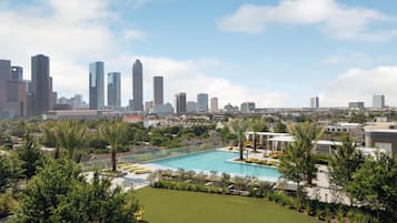 A city skyline with modern high-rise buildings, a swimming pool, and lush greenery.