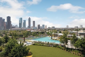 A city skyline with modern high-rise buildings, a swimming pool, and lush greenery. - Thompson Houston, by Hyatt (Houston)