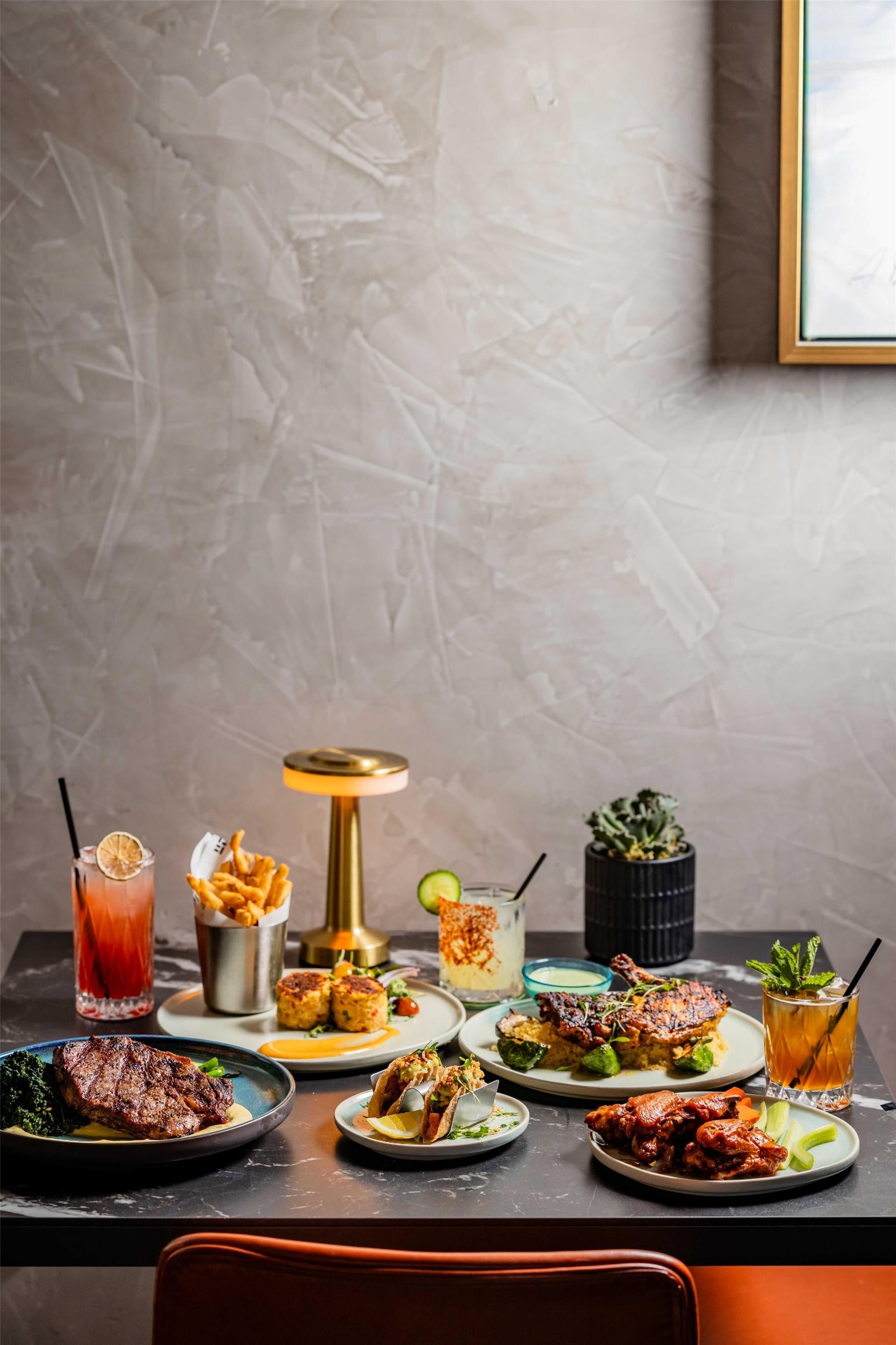 A dining table with various dishes and drinks, a small potted plant, and a framed picture on the wall.