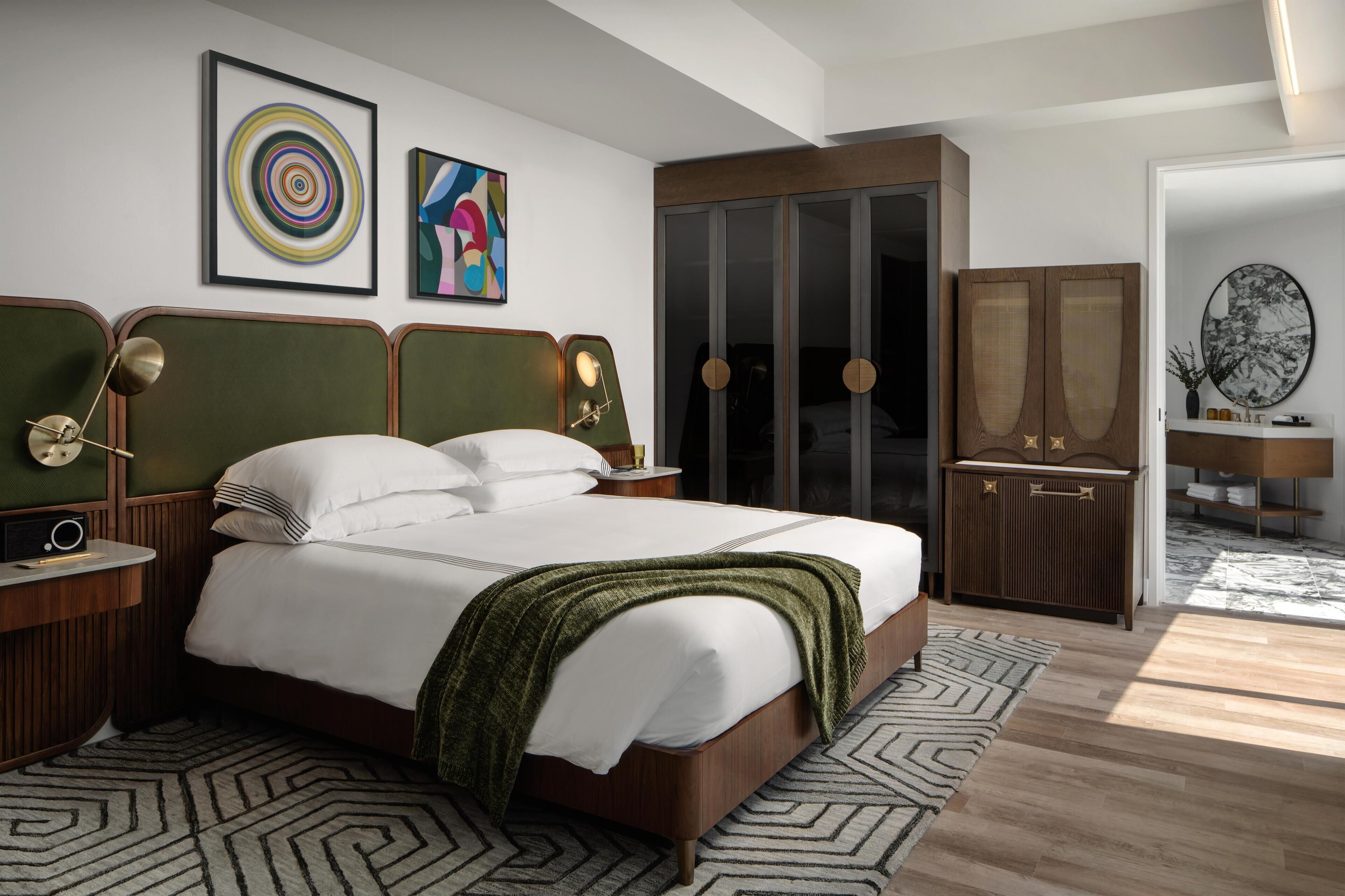 A modern bedroom with a large bed, a nightstand, a dresser, and a wardrobe.