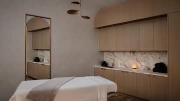 A modern bathroom with a large mirror, wooden cabinets, a marble countertop, and a bed with a blanket.