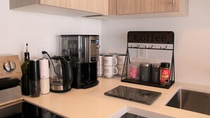 Een keuken met een koffiezetapparaat, koffiemokken en een bord met de tekst 'koffie'.