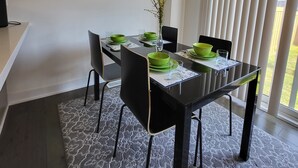 Een eetgedeelte met een zwarte tafel, groene kommen en een lijst met een afbeelding aan de muur.