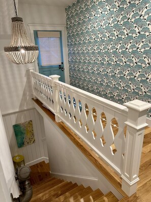 Stunning staircase with a decorative balustrade and pendant light, set against a beautiful floral-patterned wall.