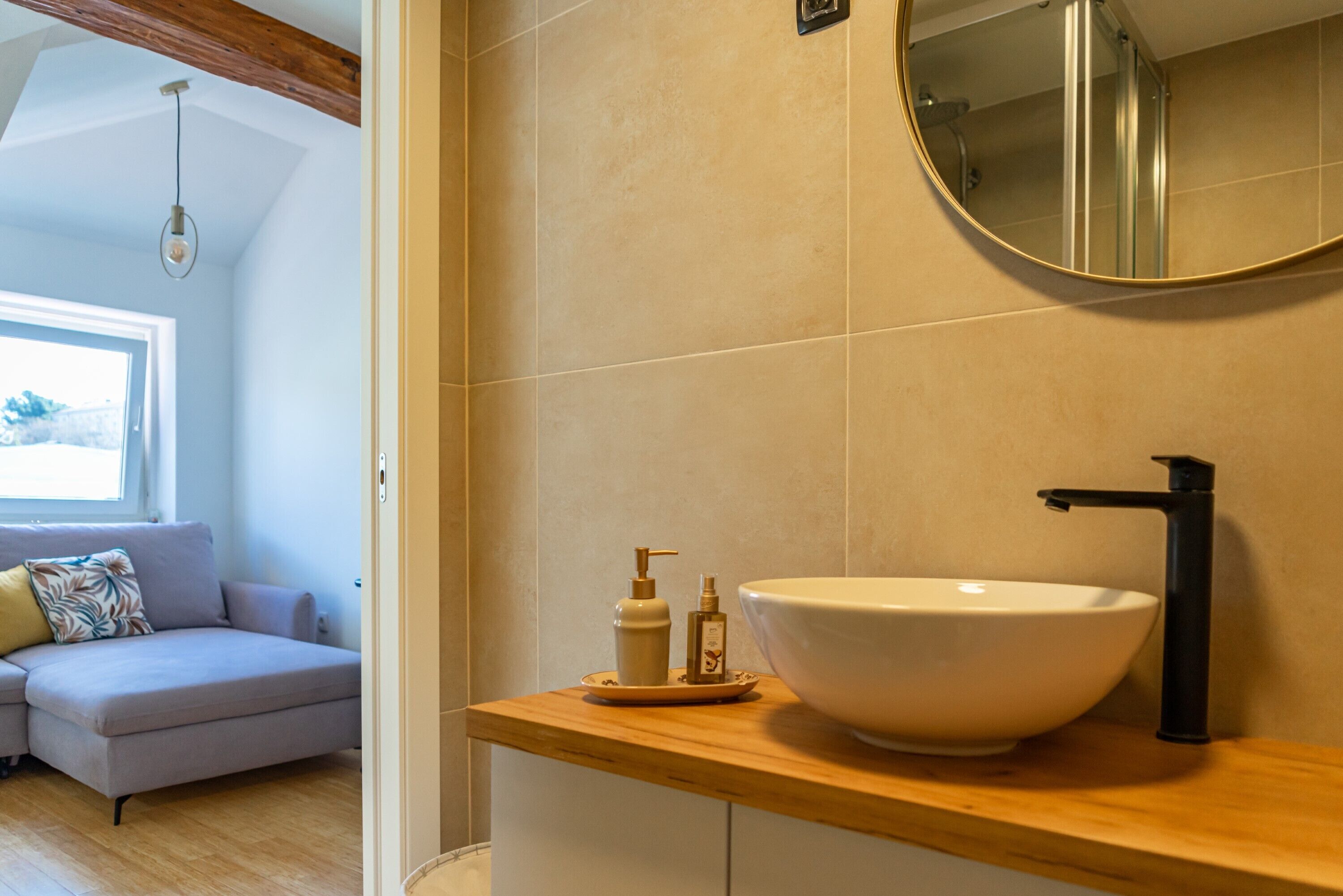 A bathroom with a large white sink, a black faucet, and a round mirror on the wall.