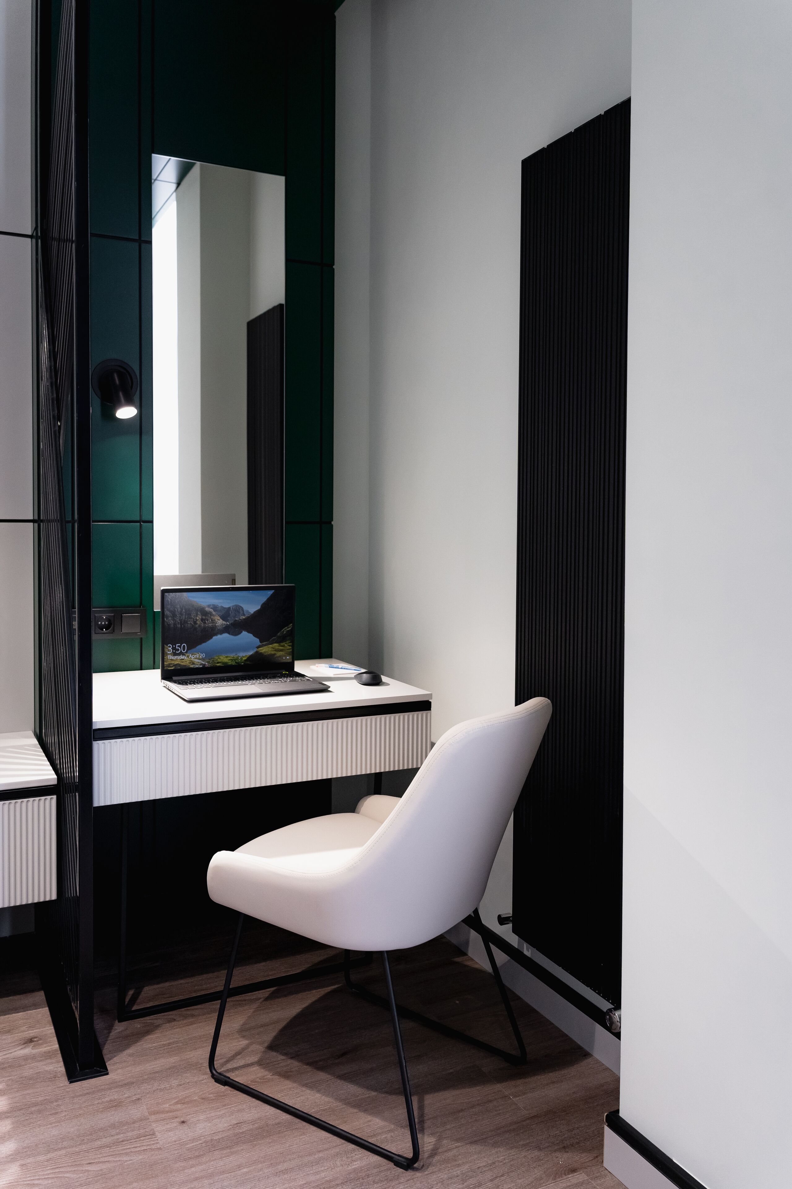 A modern office space with a white desk, a laptop, and a white chair.