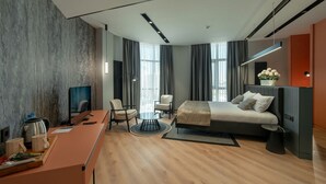 Een moderne hotelkamer met een groot bed, een bureau met een computer, een stoel en een televisie.